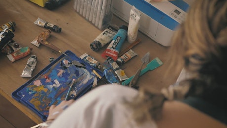 Painter working on an artwork in her home studio with oil paints