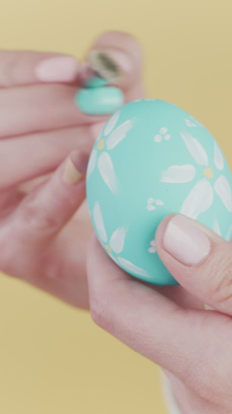 Painting flowers on an easter egg.