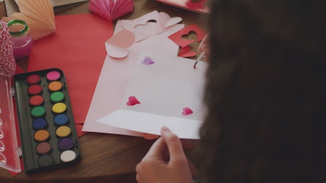 Painting hearts on a Valentine's card.