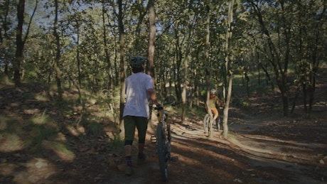 Pair of cyclists riding slowly through a forest.