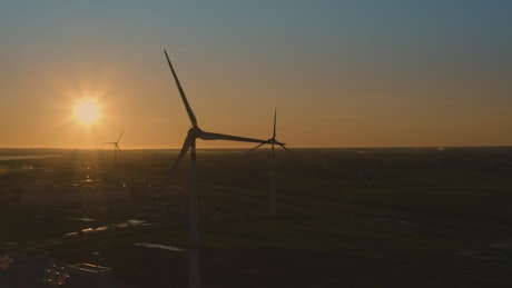 Panorama of a wind power plant with the sunset in the background.
