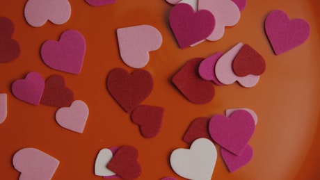 Paper shape hearts on an orange surface.