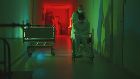 Paramedic driving a patient in a wheelchair in a creepy hospital.