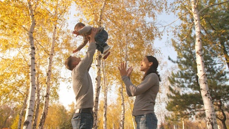 Parents playing with their little son in the park.