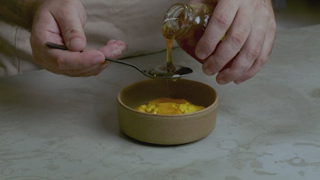 Pastry chef adding honey to a mixture.