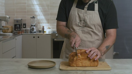 Pastry chef cutting a loaf into slices.