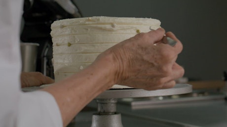 Pastry chef decorating a cake with edible pearls.