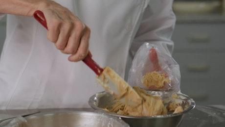 Pastry chef filling a piping bag.