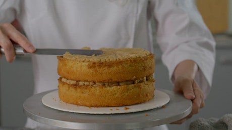 Pastry chef putting filling in a cake.
