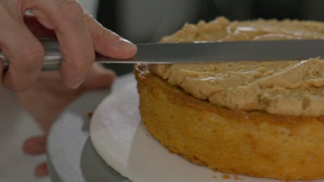 Pastry chef putting the filling on a cake.