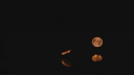 Pennies falling on a reflective surface with a dark background
