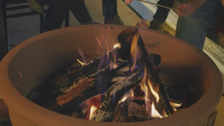 People burning marshmallows over a campfire.