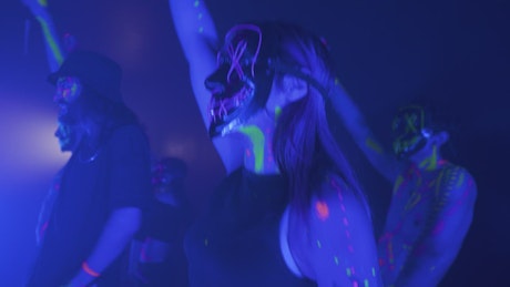 People dancing with neon masks in the dark