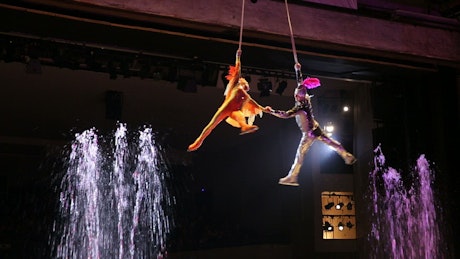 Performer spinning above bright fountains