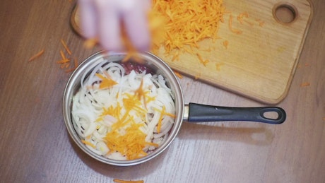 Person adding grated carrot to a recipe.