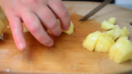 Person cutting cubes potatoes