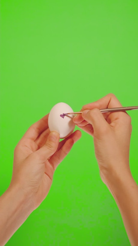Person decorating an egg with hearts
