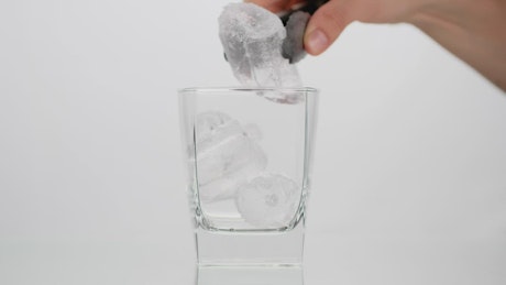 Person fills a glass with cola on white background.