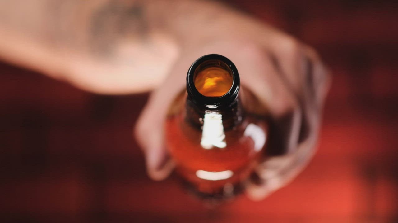 ⁣Person pouring beer from a g LIVE DRAW lass bottle