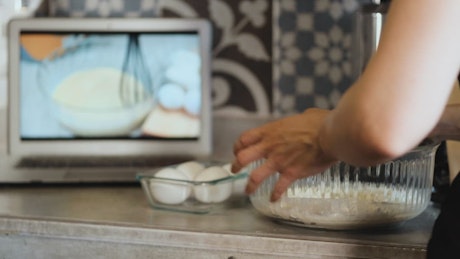 Person preparing a recipe with an online tutorial.