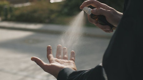 Person sanitizes his hand with spray