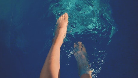 Person splashing feet in a pool.