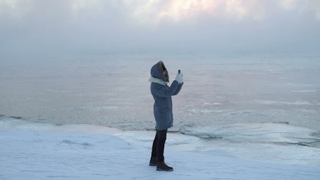 Person taking pictures with his cellphone on ice.