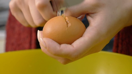 Person using a knife to break an egg shell.