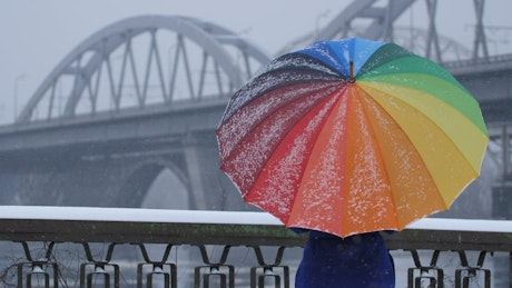 Person with a colorful umbrella on a snowy day.