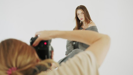 Photographer shoots model in white studio.