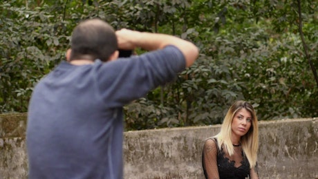Photographer using a camera to take pictures of a model in a park.