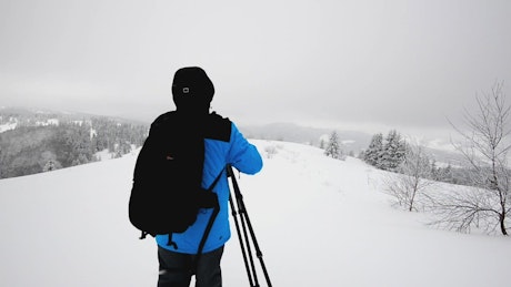 Photographer with a camera and tripod in the snow.
