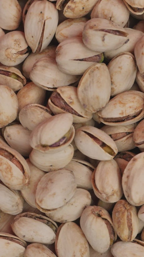 Piled up pistachios spinning seen up close.