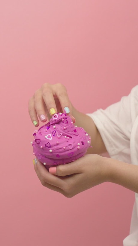 Pink plasticine ice cream in the hands of a woman.