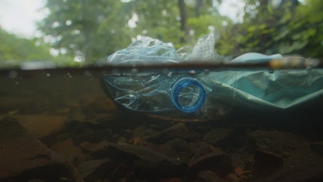 Plastic waste lying in a stream.