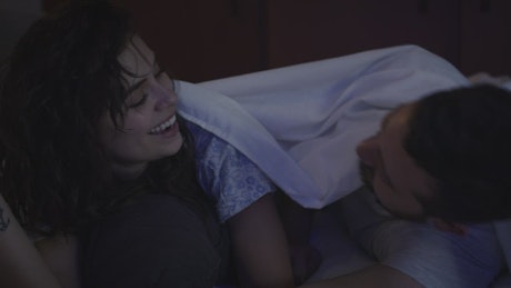 Playful couple having fun between the sheets
