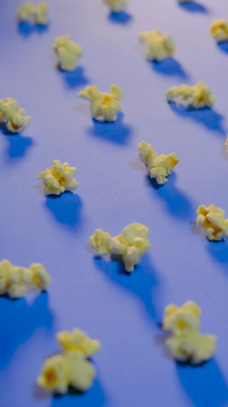 Popcorn on a blue surface changing size in stop motion.