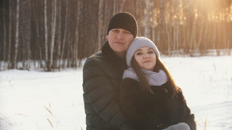 Portrait of a couple embracing in a snowy forest.
