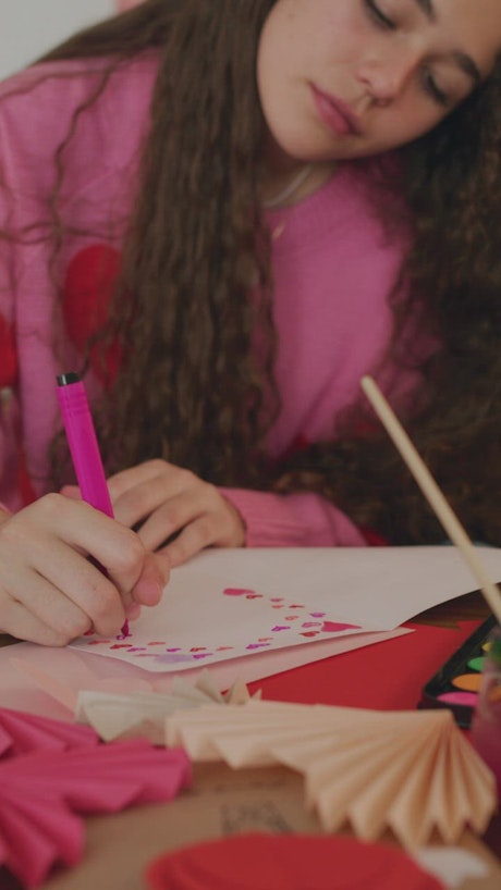 Portrait of a girl making a card for Valentine's Day.