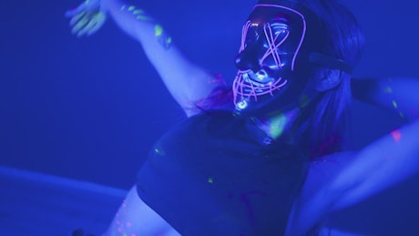 Portrait of a girl with a neon mask dancing dynamically