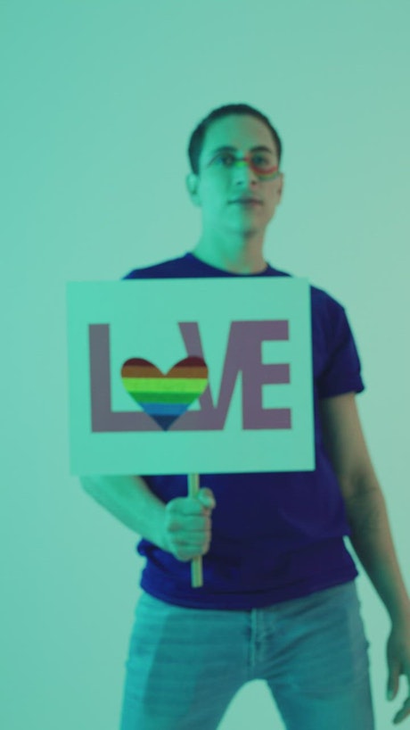 Portrait of a LGBT man with a sign with the word LOVE.