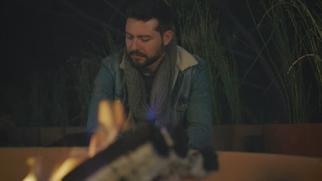 Portrait of a man warming his hands by a campfire.