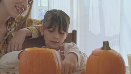 Portrait of a mother and daughter making halloween pumpkins.