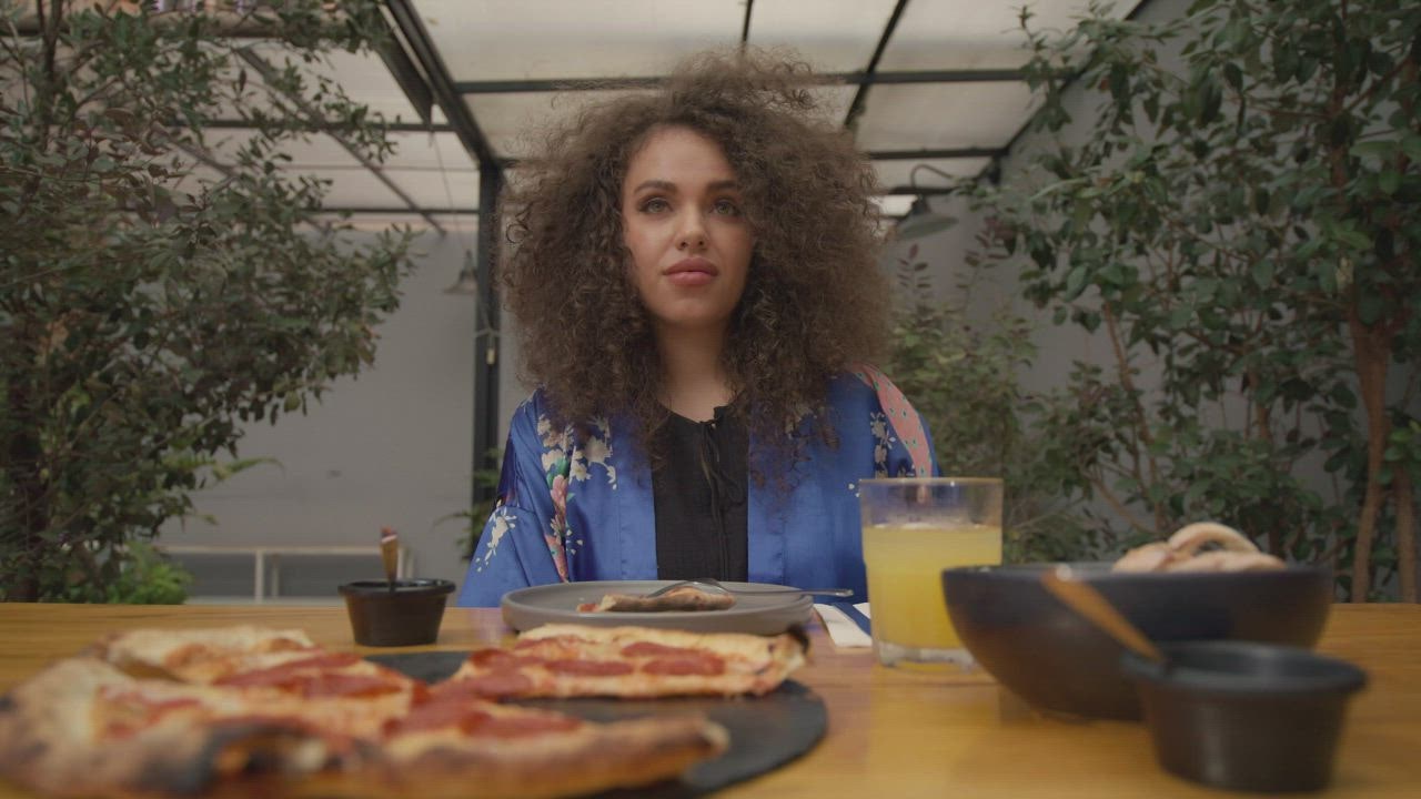 Portra 888 menggambarkan seorang wanita yang sedang makan pizza saat makan siang