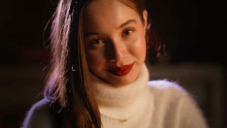 Portrait of a young woman with red lips smiling to the camera.