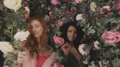 Portrait of two funny girls among many flowers