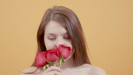 Portrait of young woman smelling red roses.
