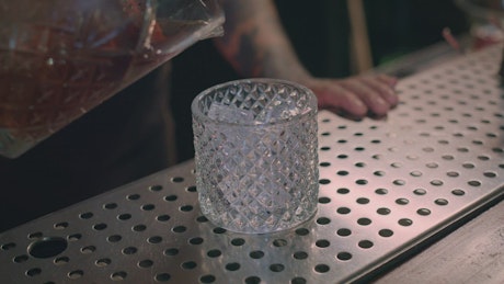Pouring a drink into a glass at a bar.