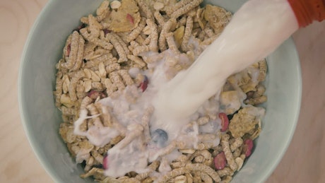 Pouring healthy cereal into a bowl until full