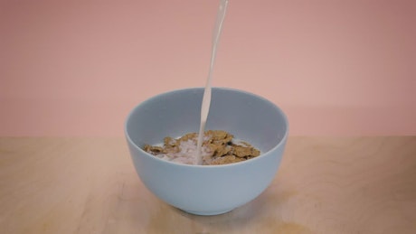 Pouring milk into a bowl with chocolate flavored cereal